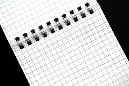 Fragment of a checkered notebook on a black background close-up. Top view. Office conceptの写真素材