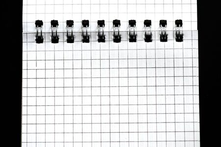 Fragment of a checkered notebook on a black background close-up. Top view. Office conceptの写真素材