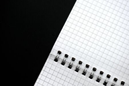 Fragment of a checkered notebook on a black background close-up. Top view. Office conceptの写真素材