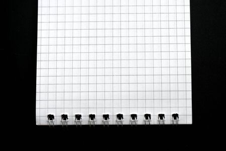 Fragment of a checkered notebook on a black background close-up. Top view. Office conceptの写真素材