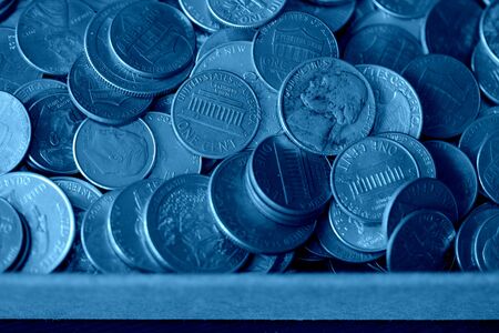 Paper box with a bunch of American cents close up. Money background blue color tonedの写真素材