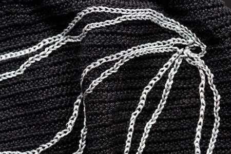 Fragment of a black crocheted bag with abstract embroidery with silver thread close-up. Top view. Hand made conceptの写真素材