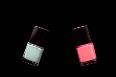 Two bottles of pink and mint color nail polish isolated on black. Beauty concept. Top view, copy spaceの写真素材