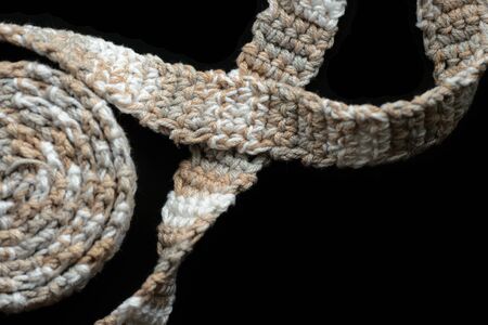 Crochet tape melange yarn brown and beige color on a black background close-up. Top view. Hand-made conceptの写真素材