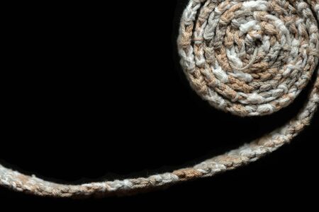 Crochet tape melange yarn brown and beige color on a black background close-up. Top view. Hand-made conceptの写真素材