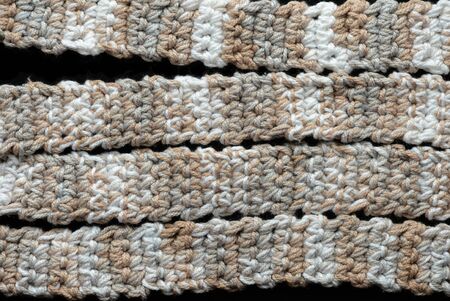 Melange yarn crocheted tape on a black background close up. Handmade concept. Top viewの写真素材