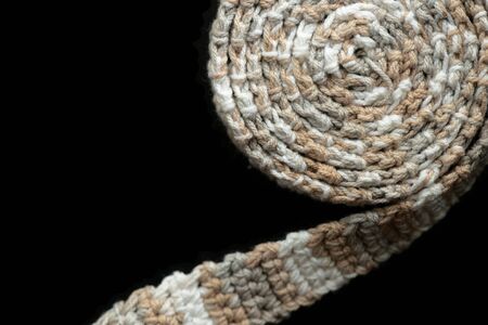 Crochet tape melange yarn rolled up on a black background close up. Top view. Handmade conceptの写真素材
