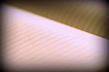 Open notebook with lined pages on a dark background. Retro style toned, vignetting