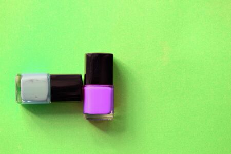 Nail polish bottles on a bright green background close-up. Manicure art cosmetic, nail art. Top view, copy spaceの写真素材