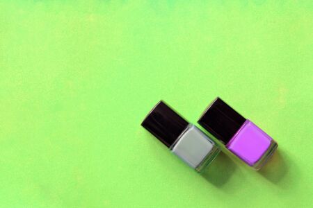 Nail polish bottles on a bright green background close-up. Manicure art cosmetic, nail art. Top view, copy spaceの写真素材