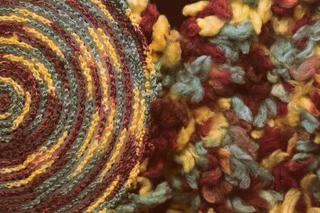Fluffy multi-colored yarn crocheted on a round plastic canvas close-up. Two parts for the handmade bag. Retro style toned. Top viewの写真素材