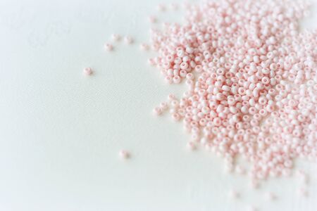 Pink seed beads scattered on the textile background close up. Handmade conceptの写真素材