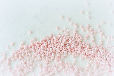 Pink seed beads scattered on the textile background close up. Handmade conceptの写真素材