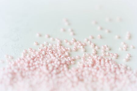 Pink seed beads scattered on the textile background close up. Handmade conceptの写真素材