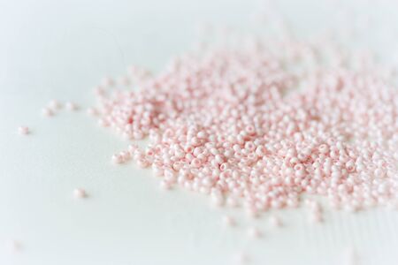 Pink seed beads scattered on the textile background close up. Handmade conceptの写真素材