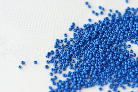 Seed beads blue color scattered on a textile background close-up. Handmade, art, creativityの写真素材