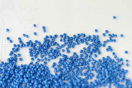 Seed beads blue color scattered on a textile background close-up. Handmade, art, creativityの写真素材