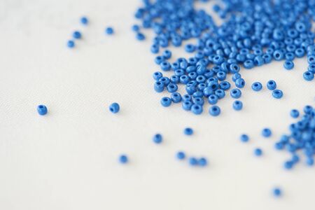 Seed beads blue color scattered on a textile background close-up. Handmade, art, creativityの写真素材