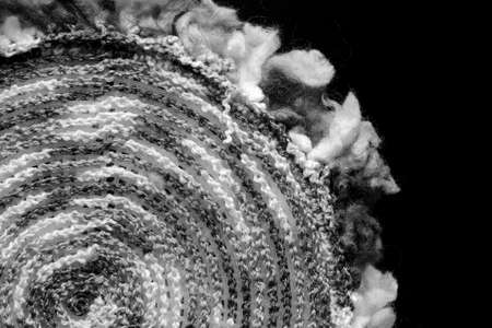 Fragment of a crocheted circle from melange threads based on a plastic canvas from the wrong side close-up. Black and whiteの写真素材