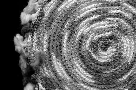 Fragment of a crocheted circle from melange threads based on a plastic canvas from the wrong side close-up. Black and whiteの写真素材