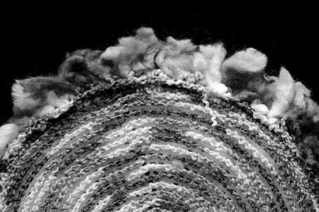 Fragment of a crocheted circle from melange threads based on a plastic canvas from the wrong side close-up. Black and whiteの写真素材