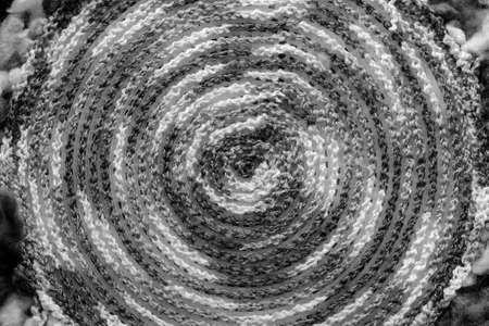 Fragment of a crocheted circle from melange threads based on a plastic canvas from the wrong side close-up. Black and whiteの写真素材