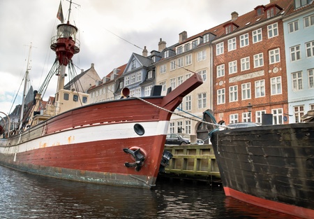 Some boats lying in the water next to houses in Copenhagen, Denmark