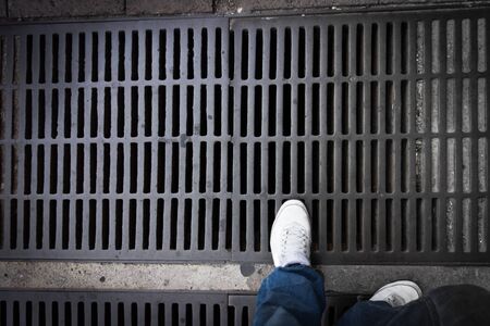 A foot standing on a drain to a sewerの写真素材