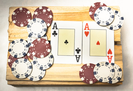 A pair of aces together with a pile of chips on a wooden supportの写真素材