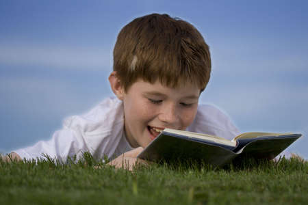 Boy reading at green field