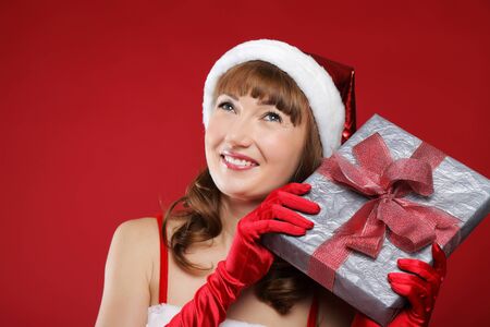 Young beautiful girl dressed as Santa holds a gift in their hands.の写真素材
