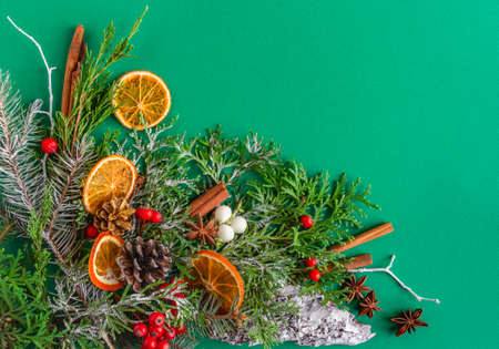 Christmas, New Year card - fir, cones, snow, cinnamon, berries on a green background. Flat lay, copy...