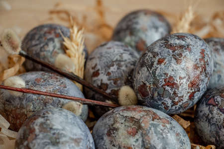 Beautiful Easter composition - colored eggs, similar to marble, ears of wheat, willow branches,...