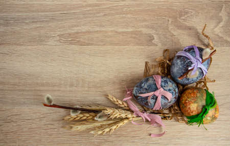 Beautiful Easter composition - colored eggs, similar to marble, ears of wheat, willow branches,...