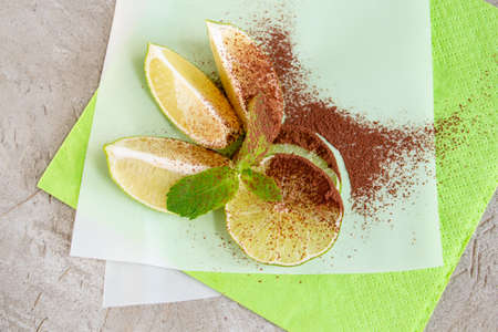 lime wedges and a sprig of mint, sprinkled with cocoa, create a beautiful juicy composition on a concrete backgroundの写真素材