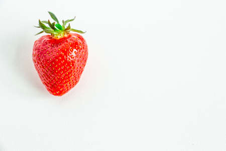 One bright strawberry on a white background, appetizing, beautiful, dietary. Place for text, copy space, flat layの写真素材