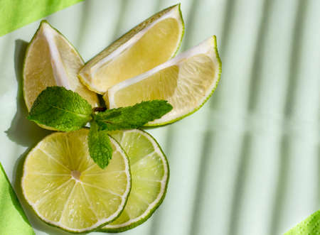 lime wedges and a sprig of mint create a beautiful juicy composition on a napkin against a concrete...