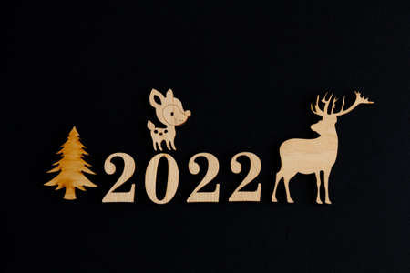 2022, Stylish christmas composition on a black background, wooden figurines of deer and fir...