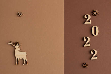 2022, Stylish christmas composition on a brown and beige background, wooden figurines, copy space....