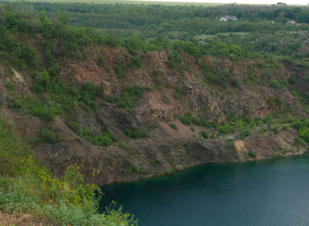rocky cliff and lake with dark blue water, quarry lakes