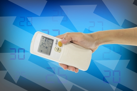Hand is holding a remote control of air conditionerの写真素材