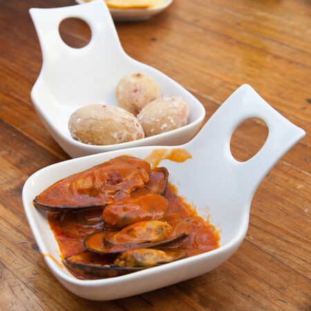 portion of mussels in red sauce on a  wooden tableの写真素材