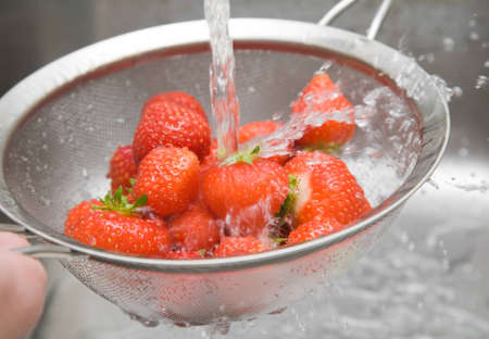 washing fresh red strawberries in a sieve, 