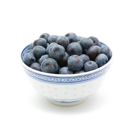 fresh ripe blueberries in a small blue bowl; isolated on white backgroundの写真素材