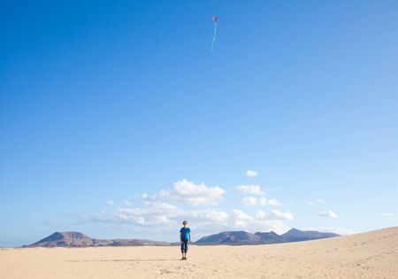  boy flies a kite in dunes of Corralejo, Fuerteventuraの写真素材