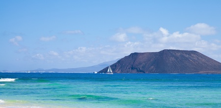Northern Fuerteventura, view towards Isla de Lobos, small white yacht in front of itの写真素材