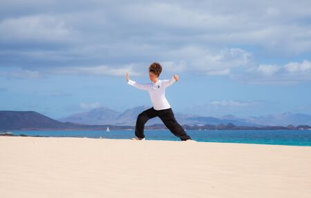Young attractive woman making Thai-chi movements in the dunes by the oceanの写真素材