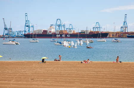 Las Palmas de Gran Canarias, sunday on a town beach, people enjoy themselvves undeterred by industrial port backgroundのeditorial素材