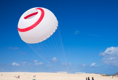 FUERTEVENTURA, SPAIN - NOVEMBER 10: Viewers watch from the ground as multicolored kites fill the sky at 25th International Kite Festival, November 10, 2012 in Dunes of Corralejo, Fuerteventura, Spainのeditorial素材
