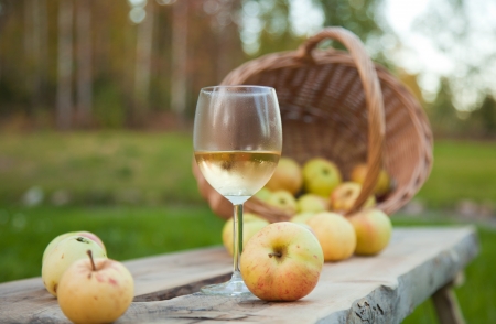 apple cider in a chilled wine glass, rustic settings with apples and wicker basketの写真素材